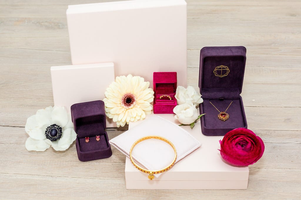 Purple, red and white jewelry boxes displaying earrings and necklaces.